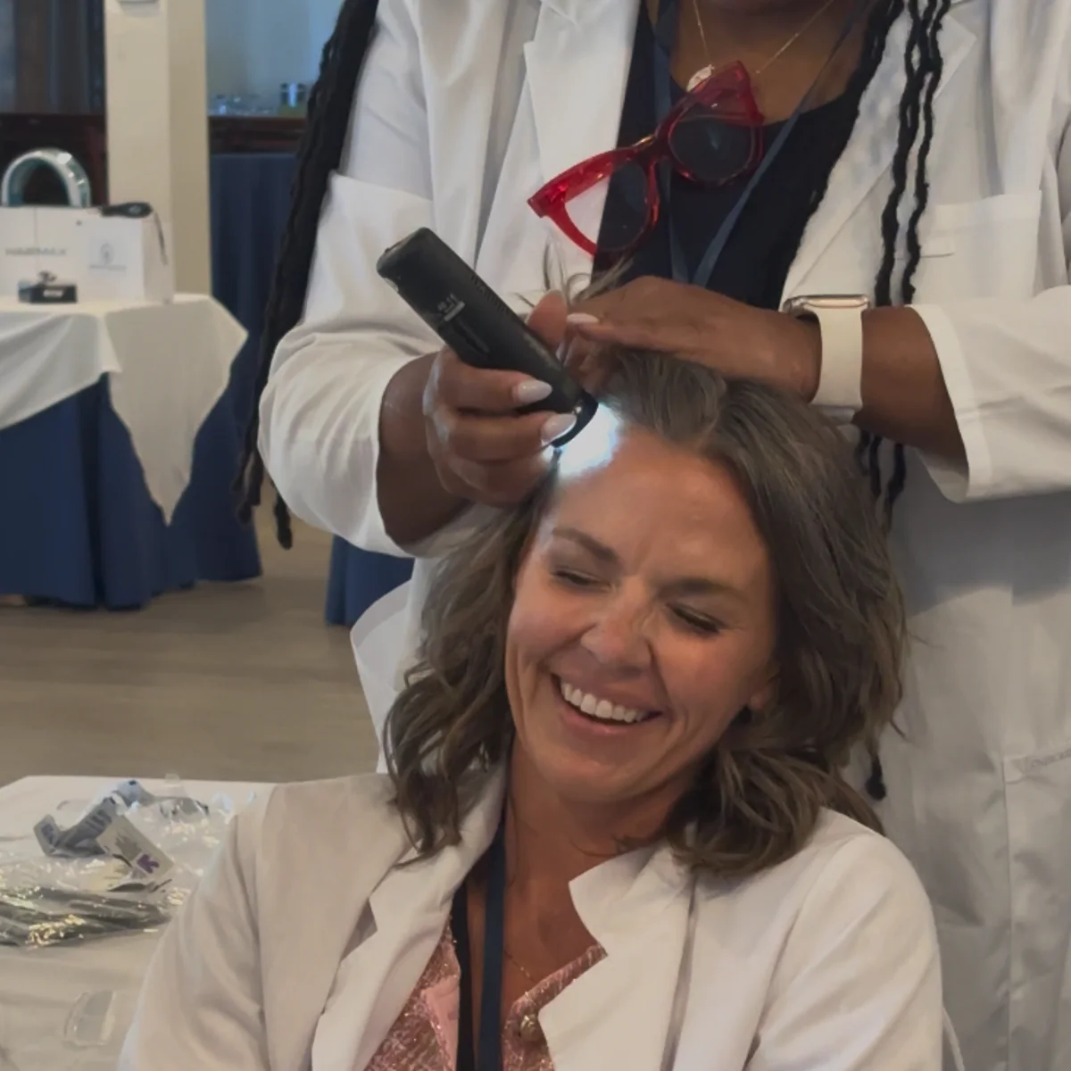 A USTI educator scoping a smiling student's scalp during a clinical class
